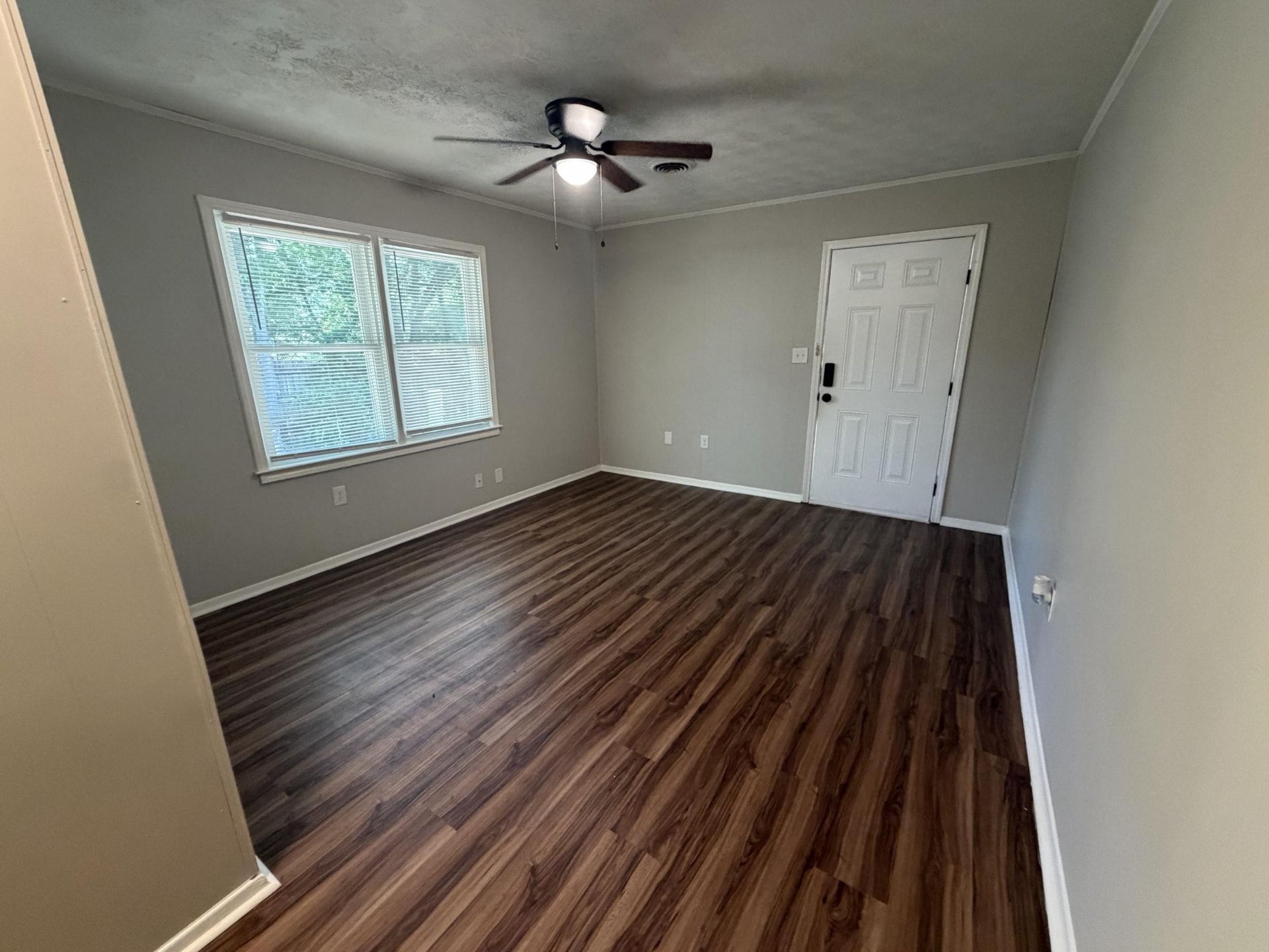 Living room with luxury vinyl plank flooring, ceiling fan, and large window