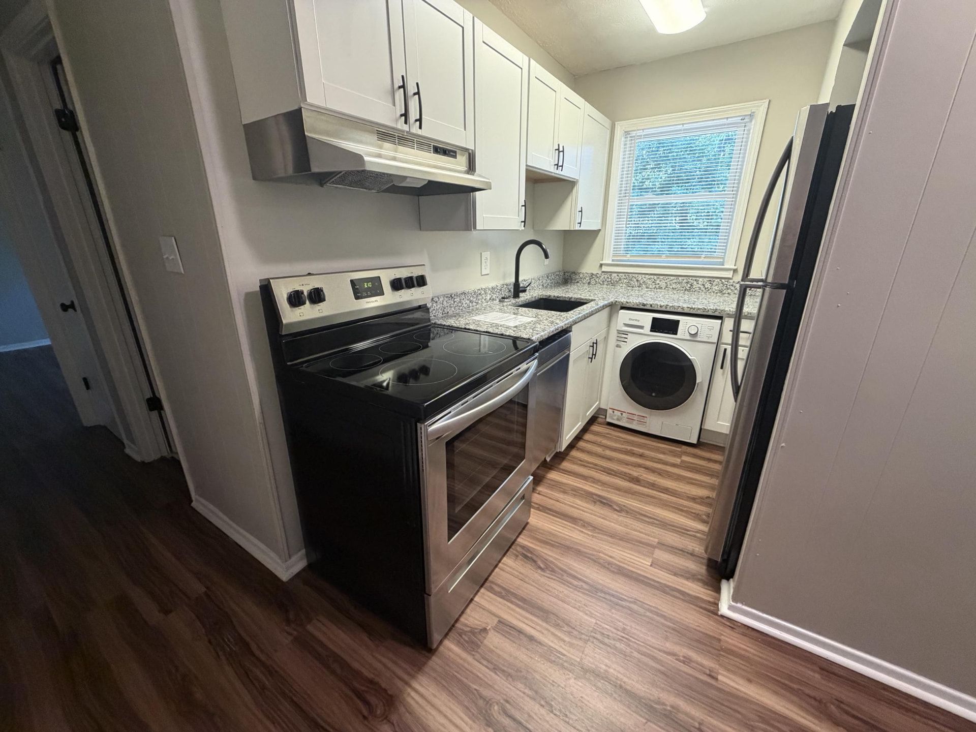 Renovated kitchen with stainless steel appliances, granite counters, and in-unit washer/dryer