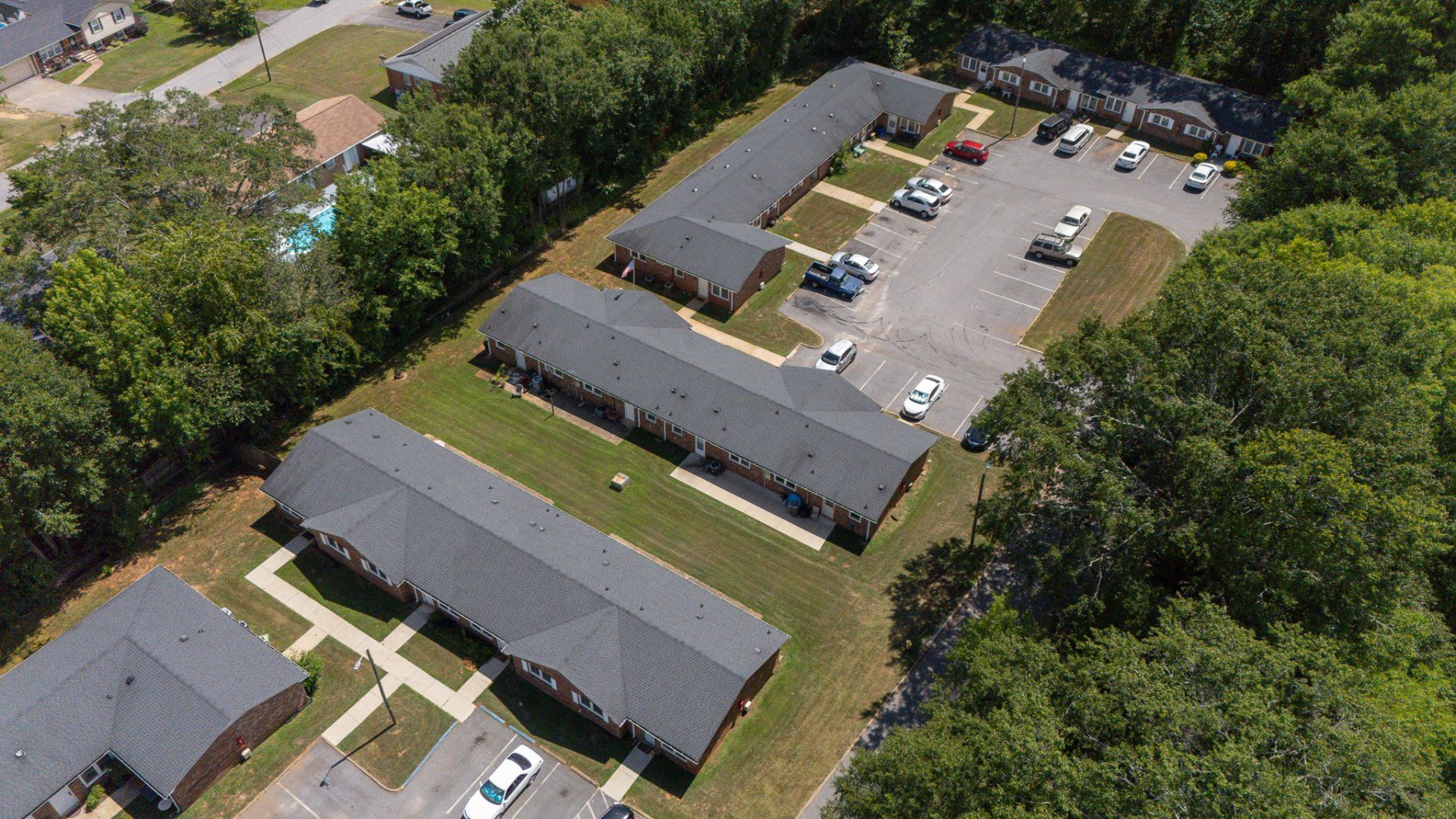 Overhead view of Creekside Apartments showing mature trees, lawns, and surface parking at each door