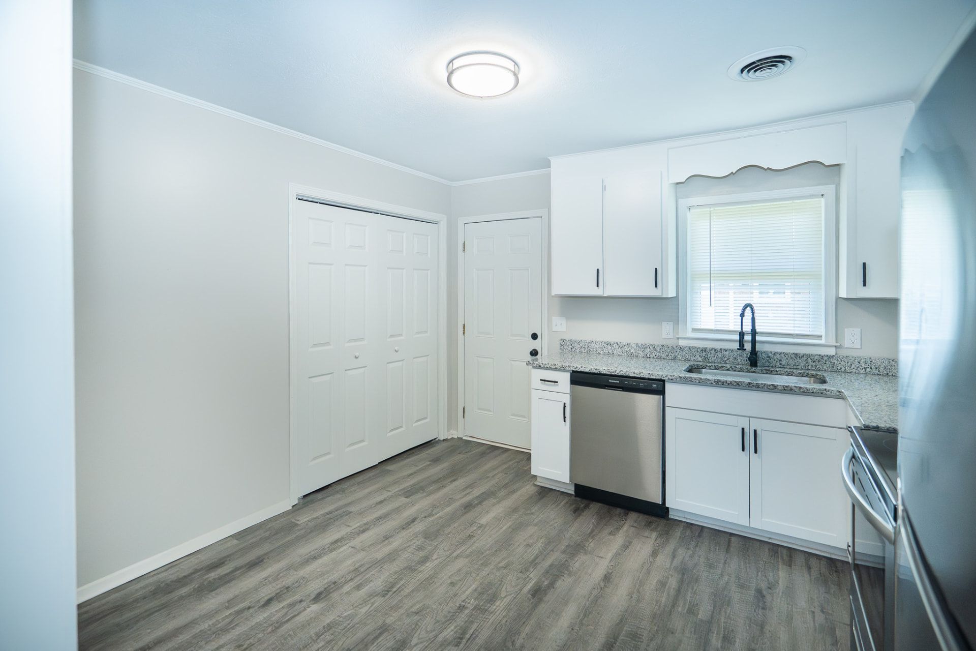 Renovated kitchen with white cabinets, granite countertops, and stainless steel appliances at Creekside Apartments