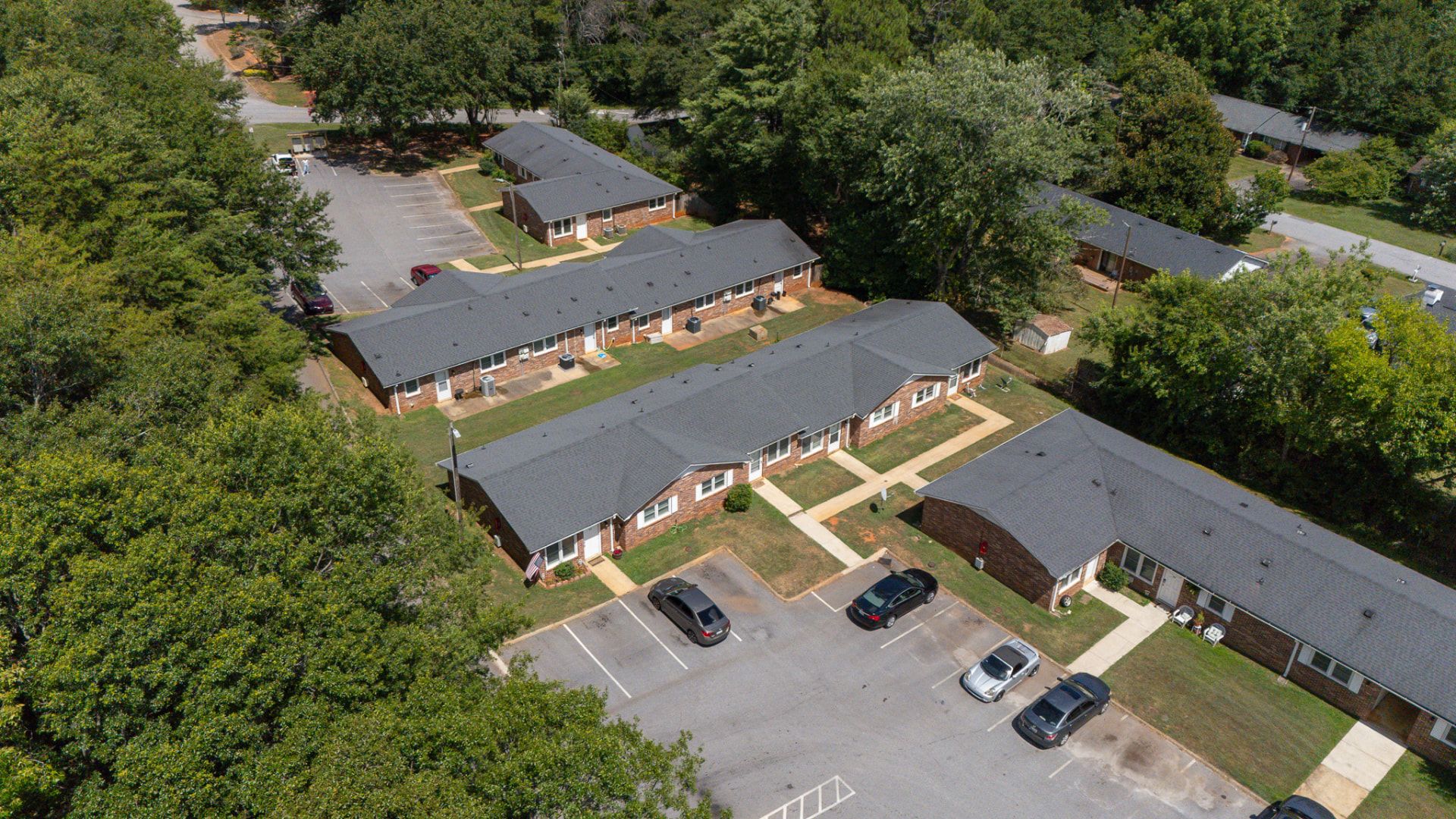 Aerial view of the single-story brick buildings and wooded grounds at Creekside Apartments in Taylors, SC