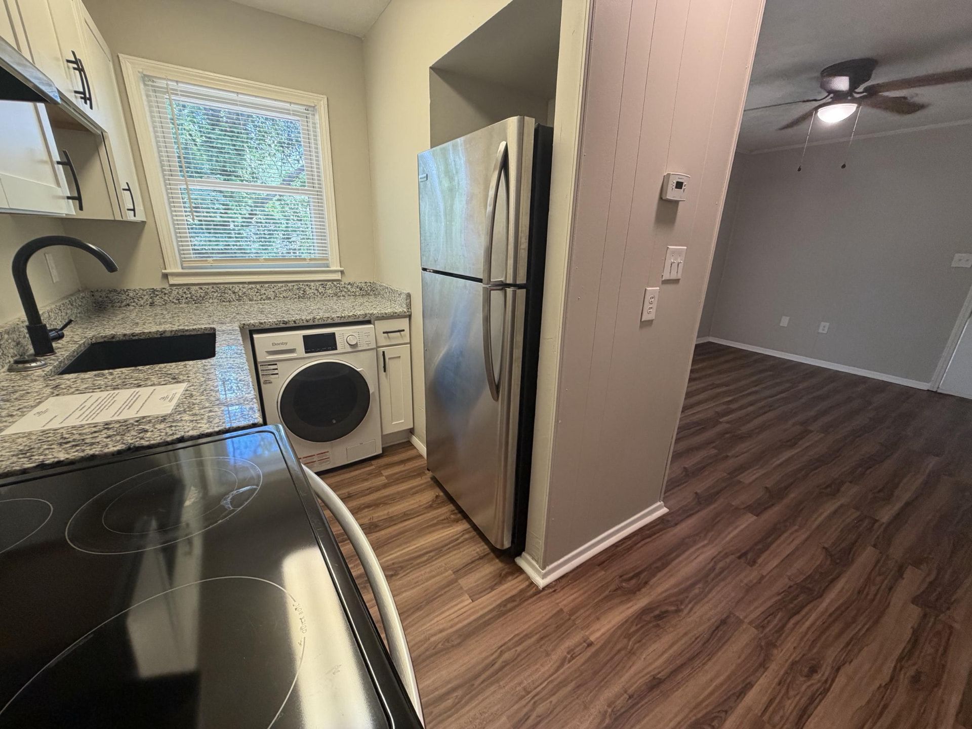 Kitchen with granite counters, stainless refrigerator, and in-unit washer/dryer beside the living room