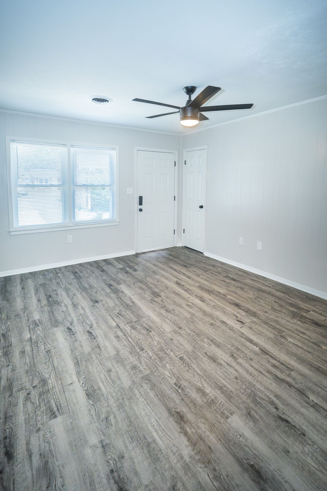Renovated bedroom with ceiling fan, window, and gray luxury vinyl plank flooring